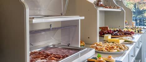 A buffet with various food items including meats, cheeses, and pastries.