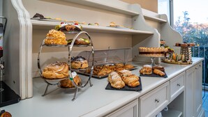 A buffet counter with various pastries and desserts displayed on shelves and trays.
