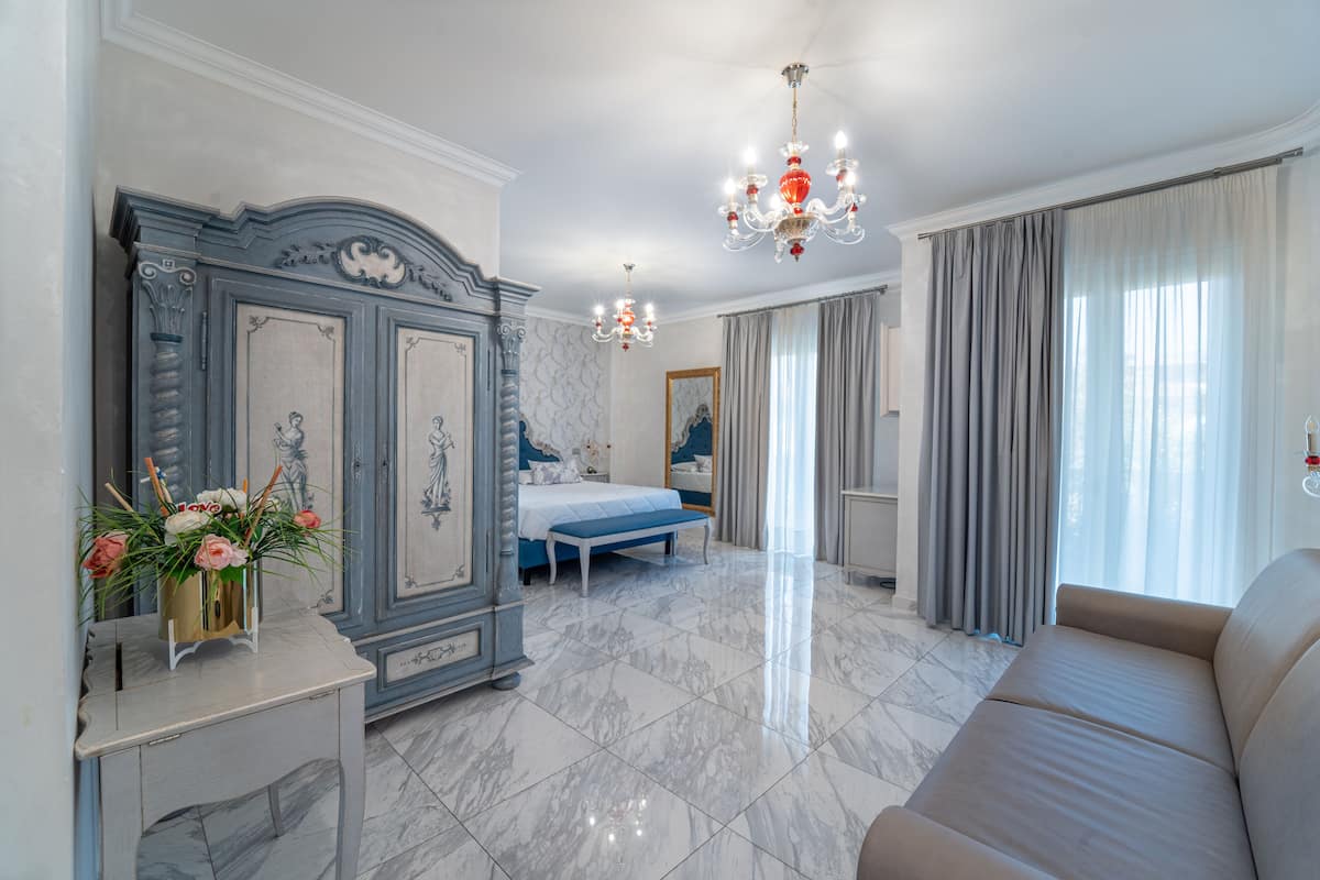 A spacious bedroom with a large bed, a vanity with a mirror, and a chandelier.