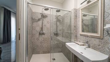 A modern bathroom with a glass-enclosed shower, a white sink, and a large mirror.