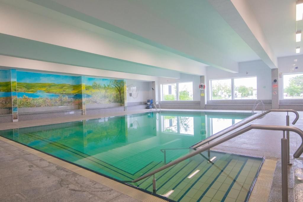 Une piscine intérieure à l’eau claire, dotée d’un sol carrelé et ornée d’une fresque murale.