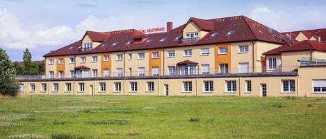 Un hotel grande con varios pisos y techo plano, rodeado por un campo cubierto de césped.