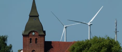 A church with a clock tower and wind turbines in the background.