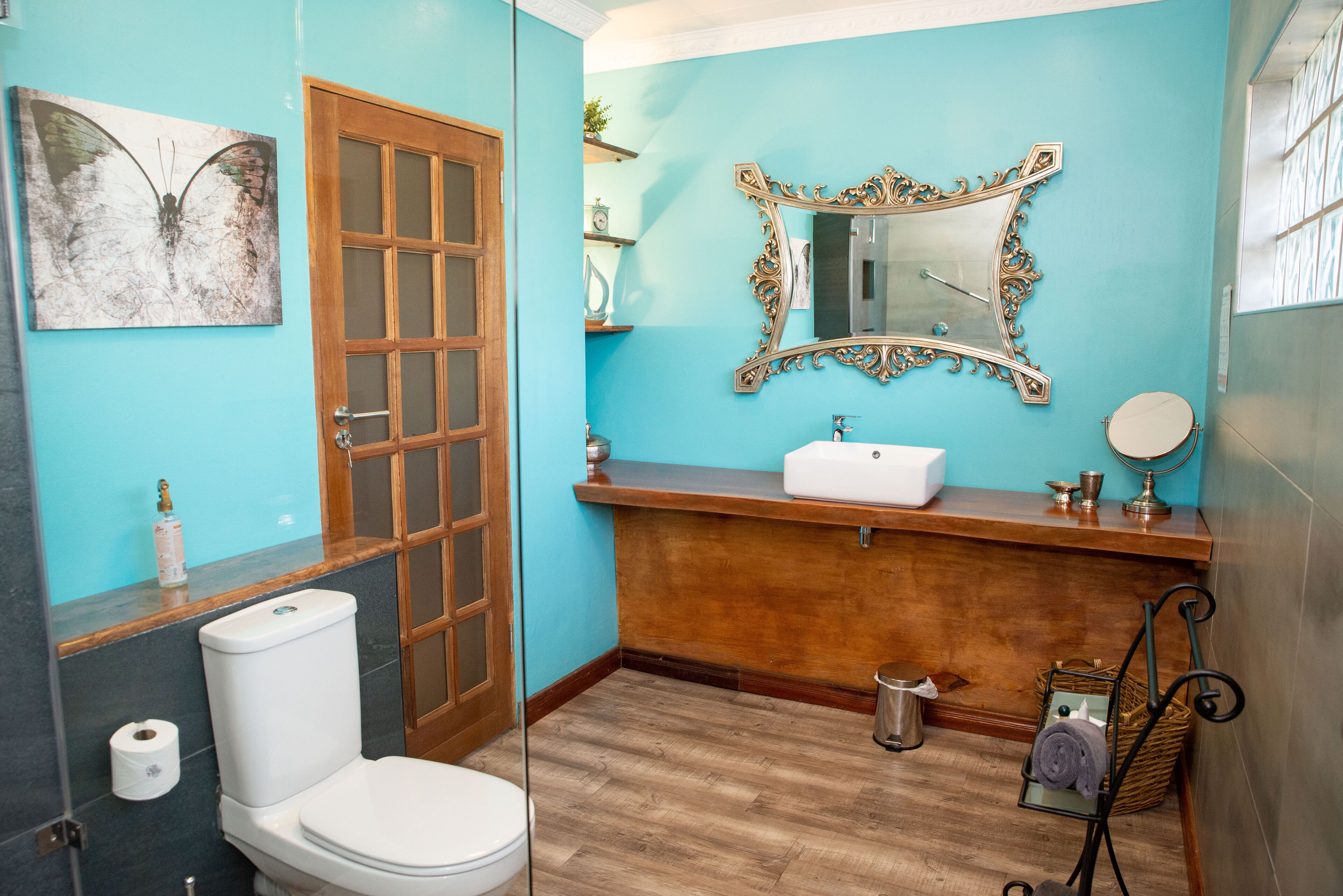 Une salle de bain avec des toilettes, un lavabo, un miroir et un plancher en bois.