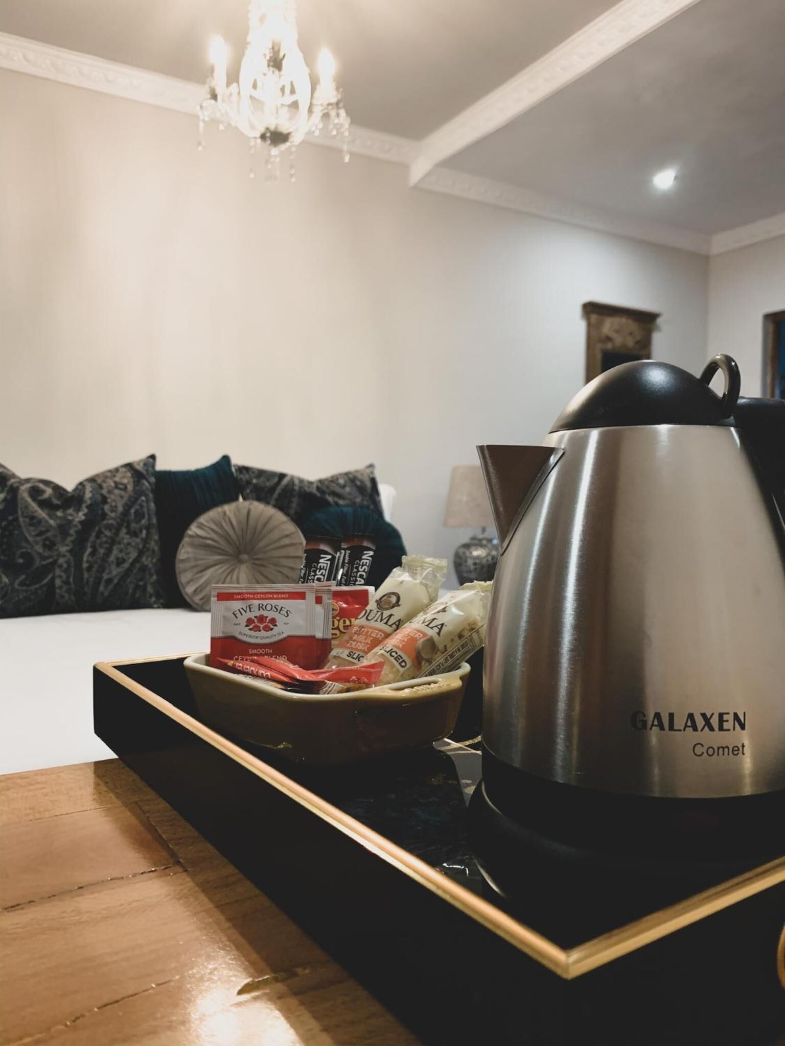 Un salon chaleureux avec une table basse moderne, une machine à café Galaxen Comet et un plateau contenant des en-cas et une boîte de thé Five Roses.