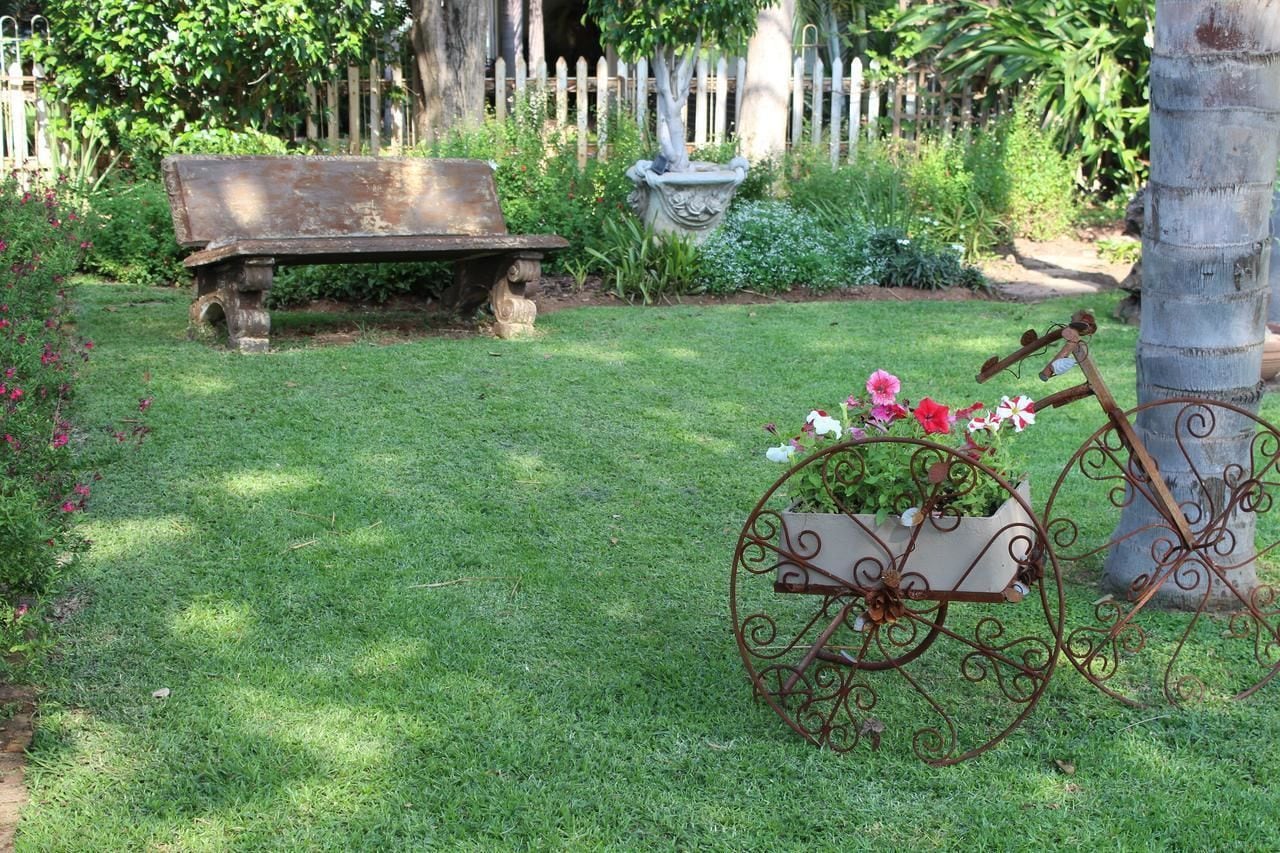 A garden with a bench, a decorative planter, and a metal cart.