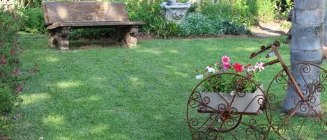 A garden with a bench, a decorative planter, and a metal cart.