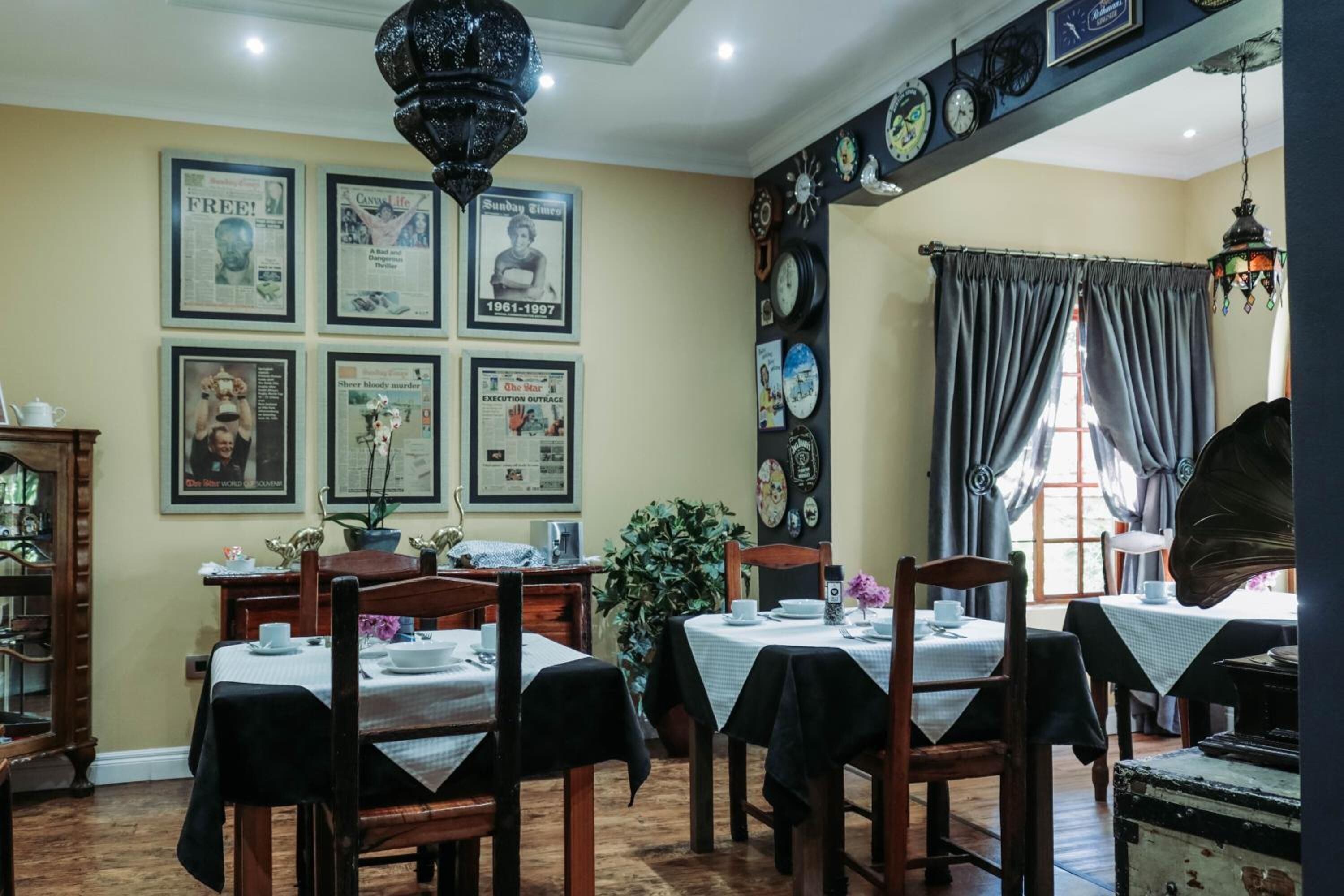 A dining area with wooden tables and chairs, framed pictures on the wall, and a chandelier.