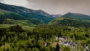 Paesaggio montuoso con fitte foreste e un gruppo di edifici dall'architettura tradizionale, probabilmente un resort o un albergo.