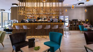 Un área de bar moderna con un separador de madera, taburetes y lámparas colgantes.