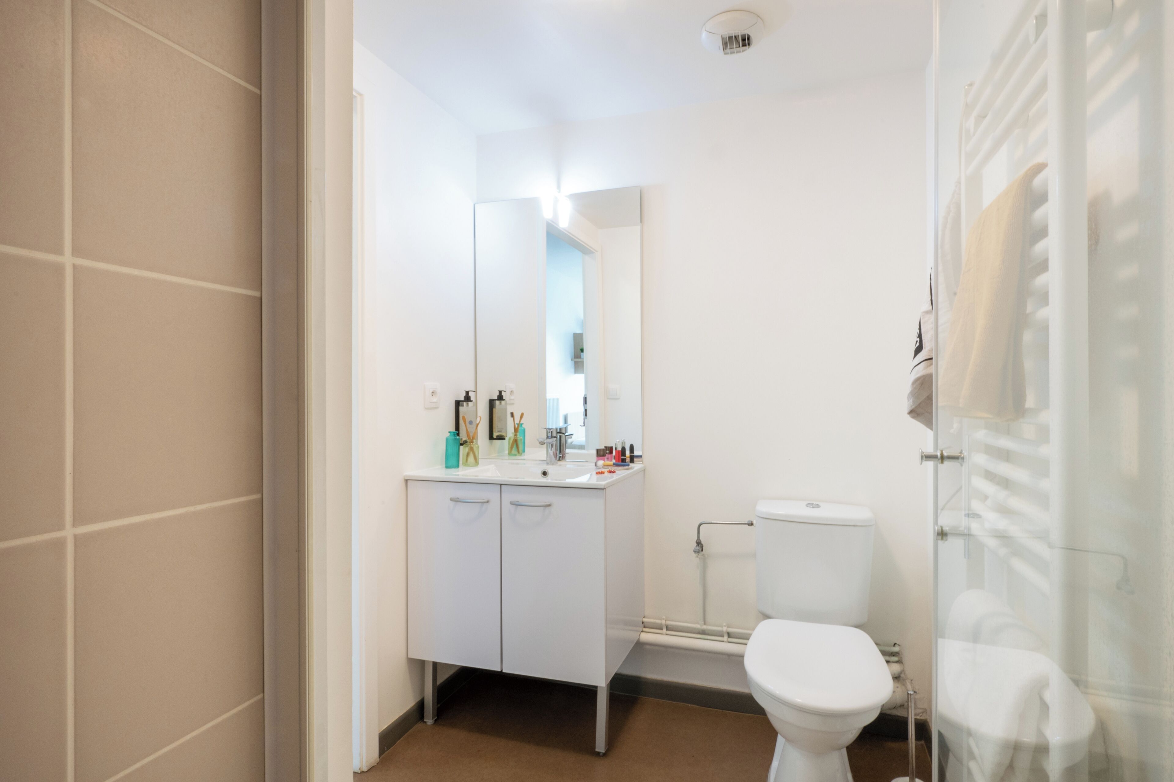 A modern bathroom with a white sink, mirror, and toilet.