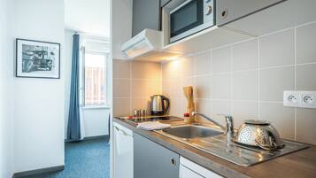 Una cocina moderna con microondas, hervidor y colador sobre la encimera.