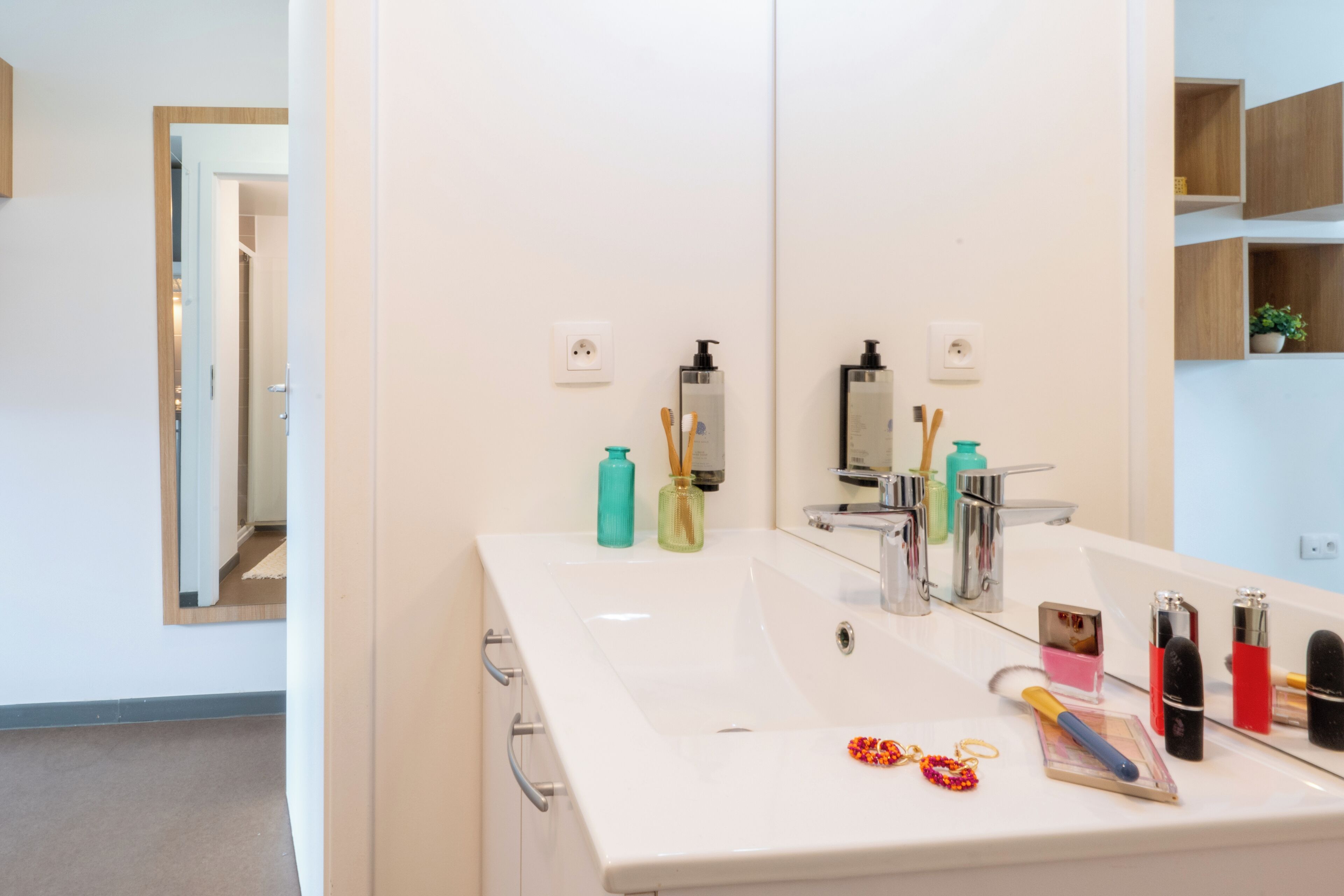 Un bagno moderno con uno specchio grande, un lavandino bianco e diversi articoli da toilette.
