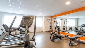 A gym with treadmills, weight machines, and a mirrored wall.