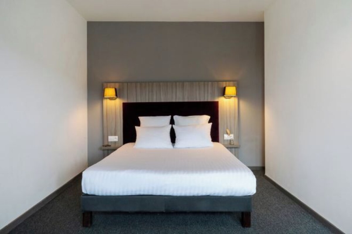 Ett hotellrum med en stor säng, två sänglampor och en sänggavel.