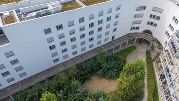 A modern building with a flat roof, multiple windows, and a central courtyard with greenery.