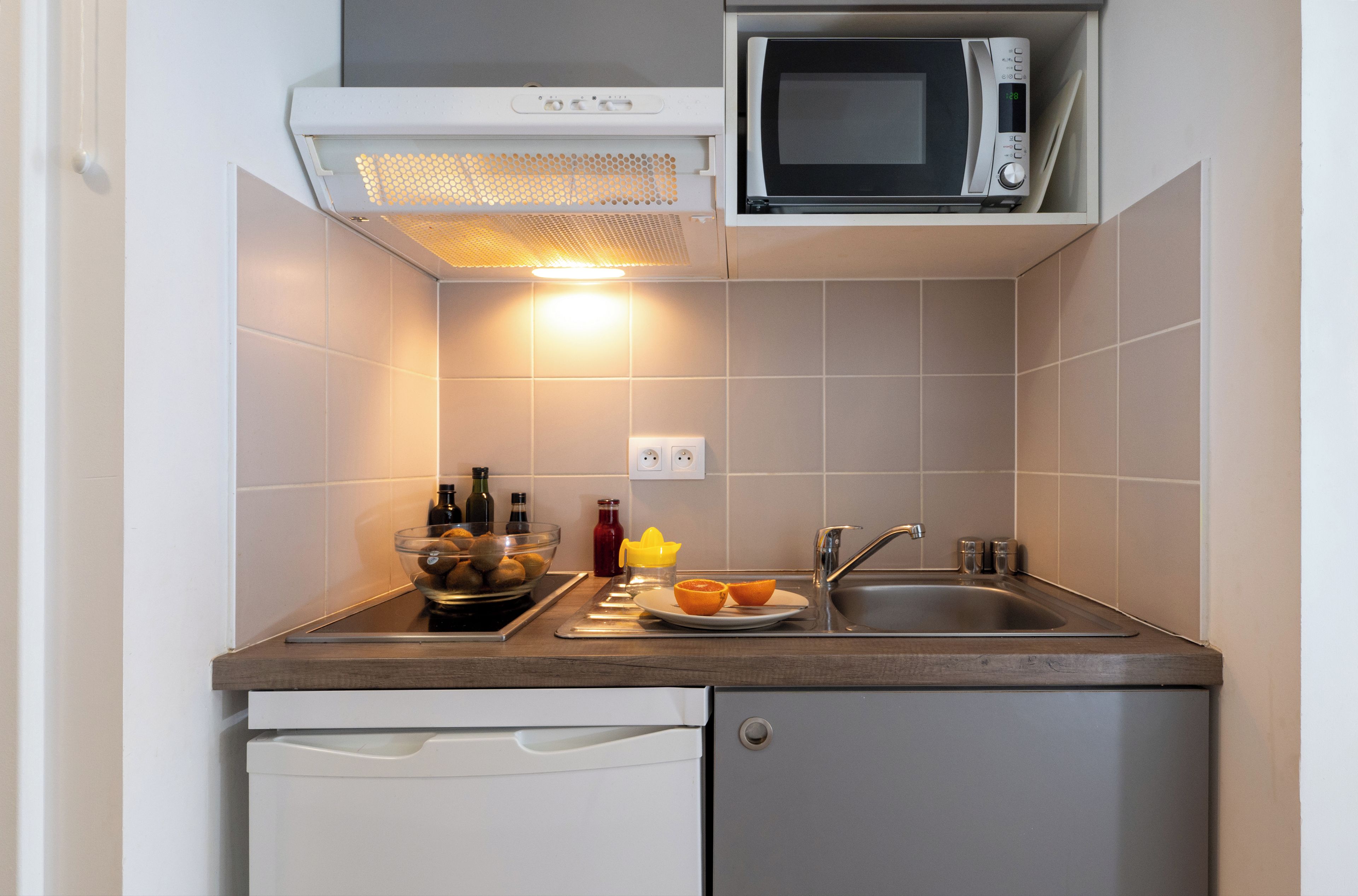 Une cuisine compacte équipée d’un four à micro-ondes, d’un évier et d’un égouttoir à vaisselle.