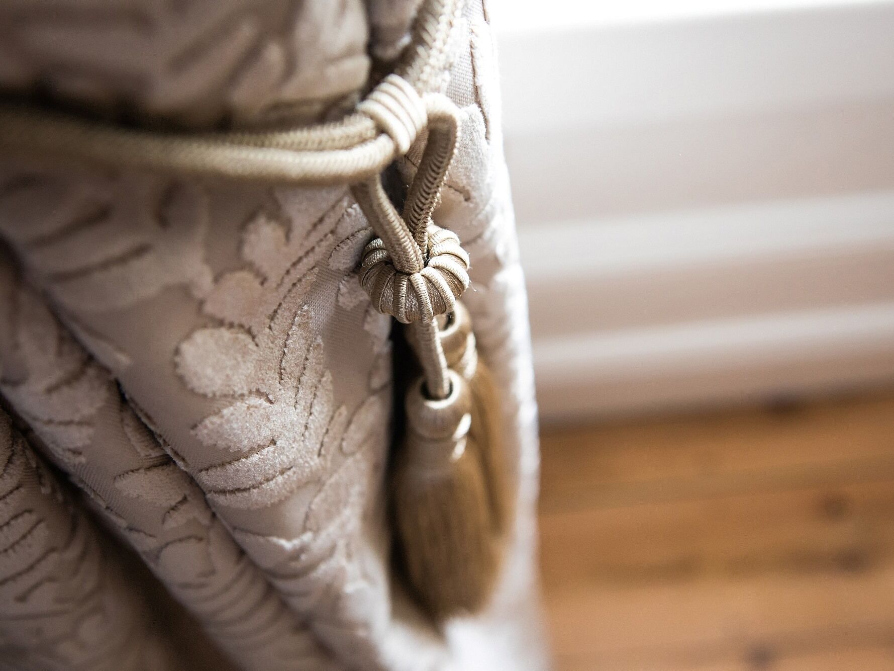 A close-up of a curtain with a tassel and a knot.