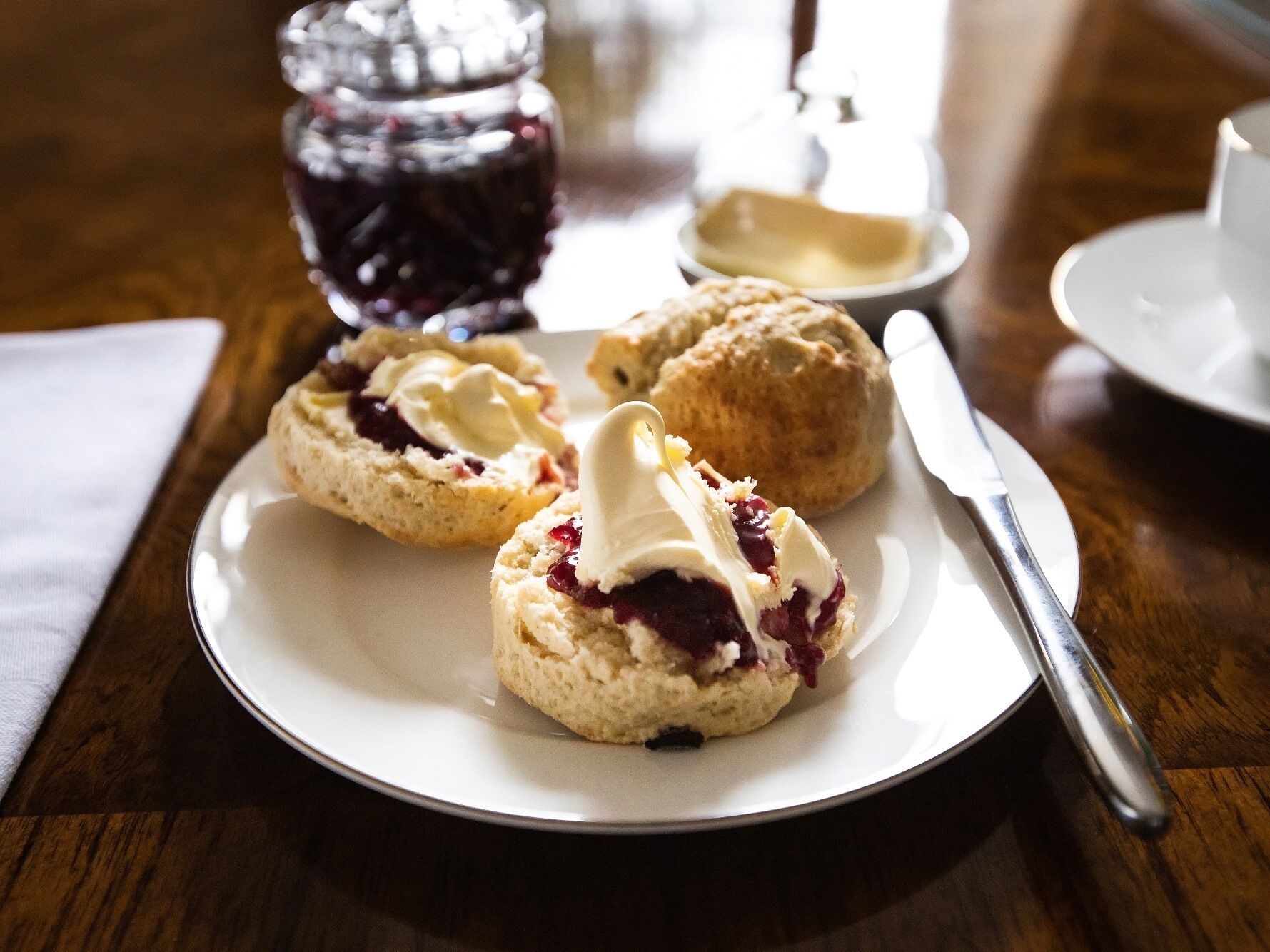 A plate with scones and clotted cream on a wooden table.