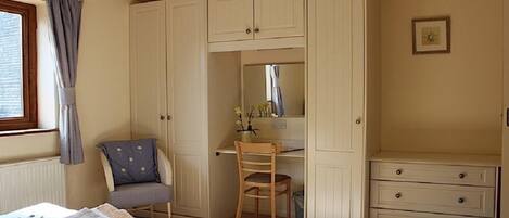 A bedroom with a bed, a desk, a chair, and a dresser.