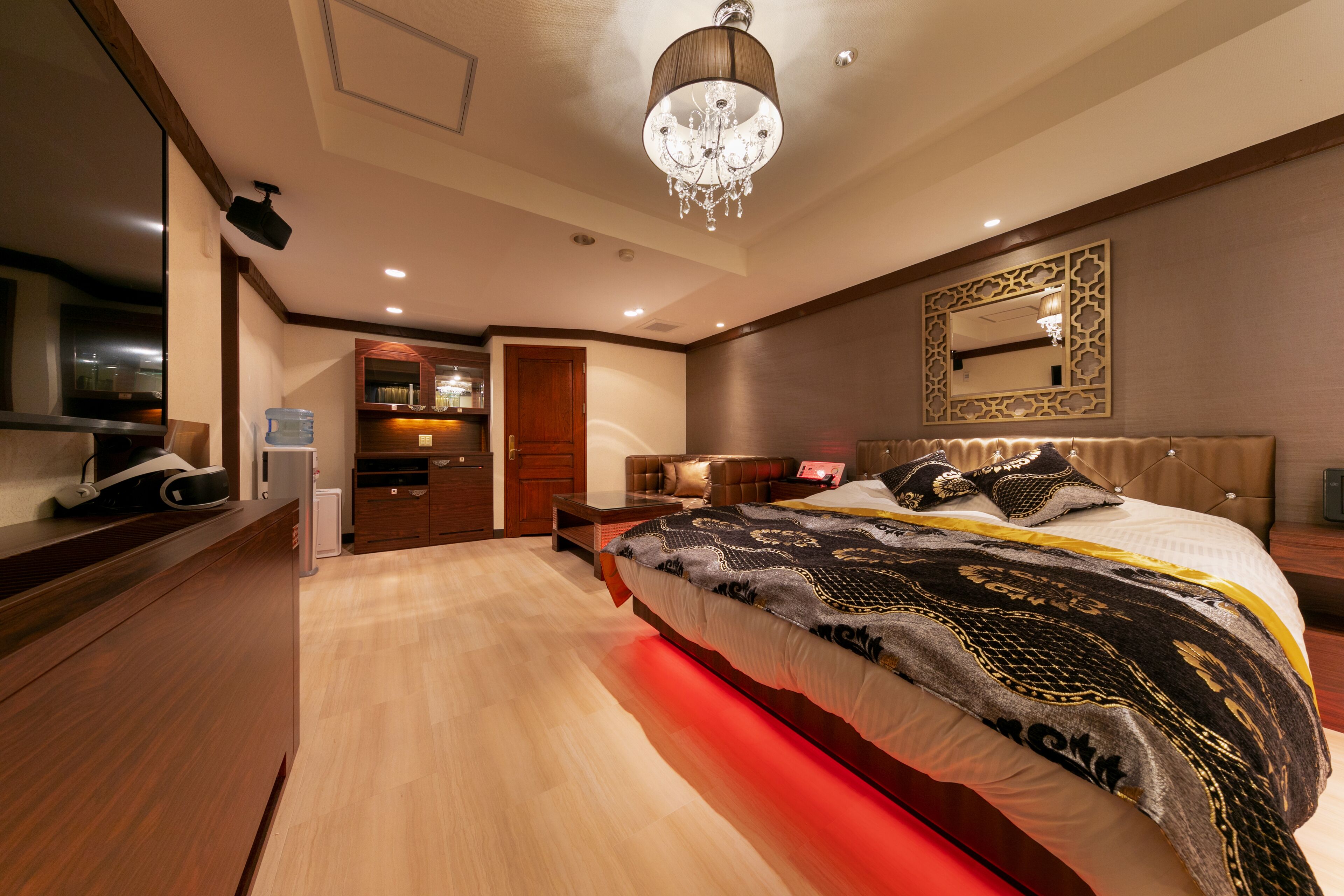 Una habitación de hotel moderna con una cama grande, una araña, un espejo y suelo de madera.