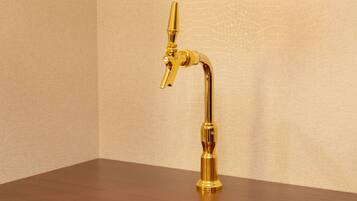 A gold-colored tap on a wooden surface against a textured wall.