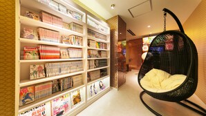 A hotel lobby with a large bookshelf filled with books and magazines, a hanging chair, and a tiled wall. - i RESORT ARTIA Luxury GIFU - Adult only (Gifu)