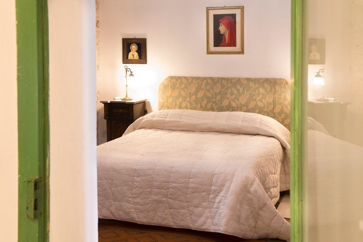 A bedroom with a bed, a nightstand, a lamp, and two framed pictures on the wall.