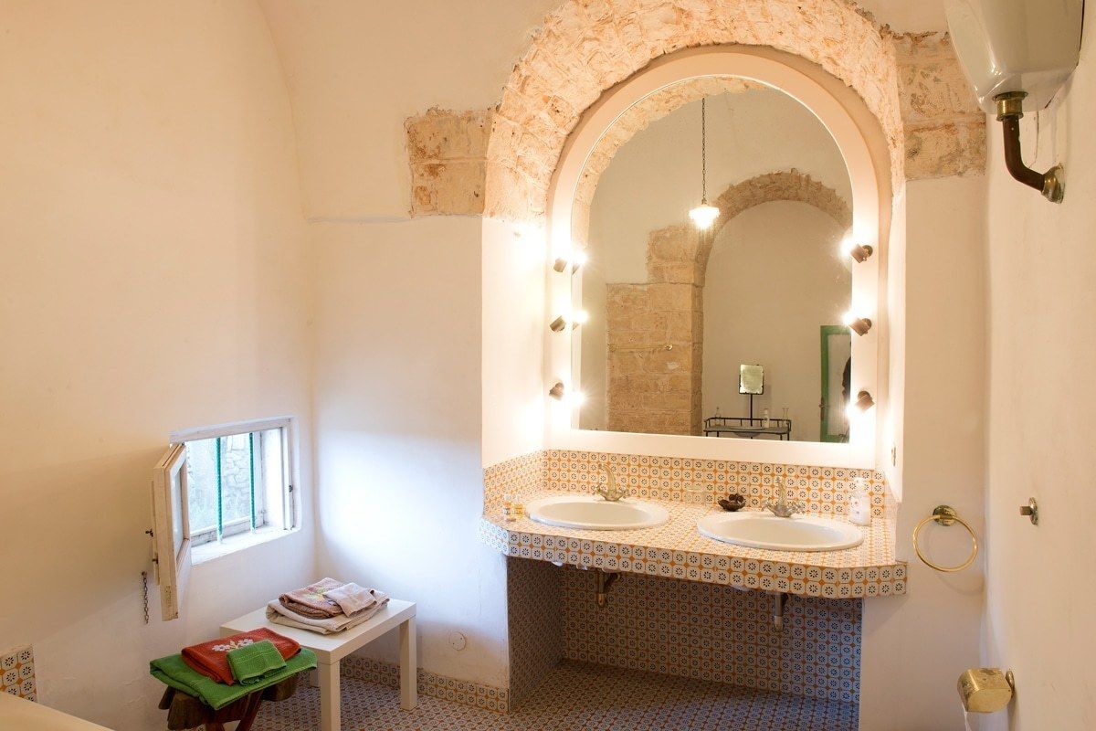 Une salle de bain avec deux lavabos, un grand miroir avec éclairage, une fenêtre et une petite table avec des serviettes.