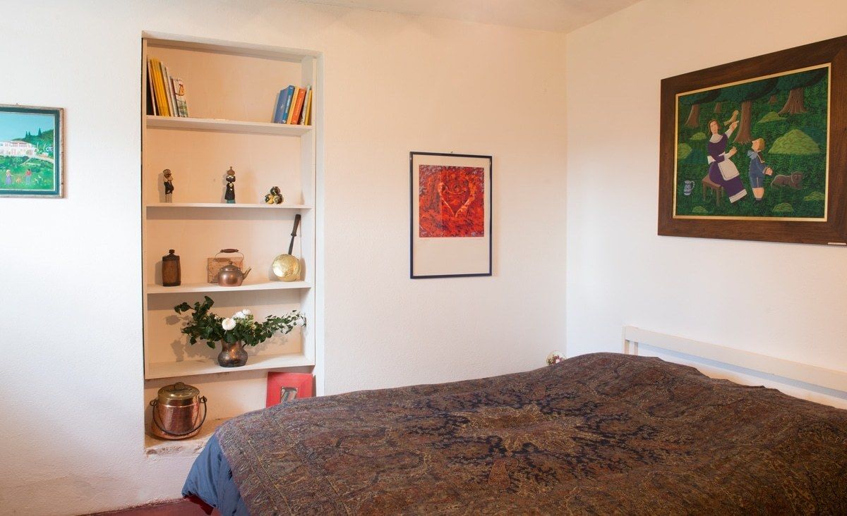 A bedroom with a large bed, a bookshelf, and a painting on the wall.