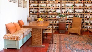A room with a wooden table, a sofa, and a large wall of wine bottles. - Masseria Murgia Albanese (Noci)