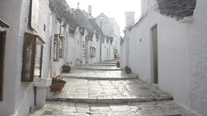 A narrow cobblestone street flanked by white buildings with tiled roofs. - Masseria Murgia Albanese (Noci)