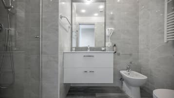 A modern bathroom with a glass-enclosed shower, a vanity with a mirror, and a bidet.
