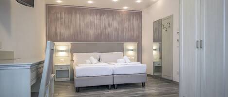 A modern bedroom with a large bed, bedside lamps, a TV, and a wardrobe.