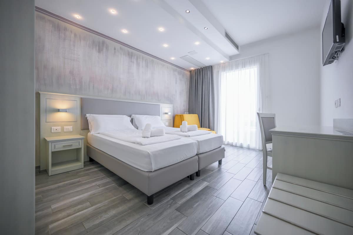 A modern hotel room with a double bed, bedside tables, a desk, and a TV.