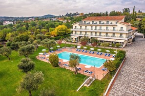 A large building with a swimming pool, surrounded by green lawns and trees. - Hotel Villa Paradiso Suite  (Moniga del Garda)