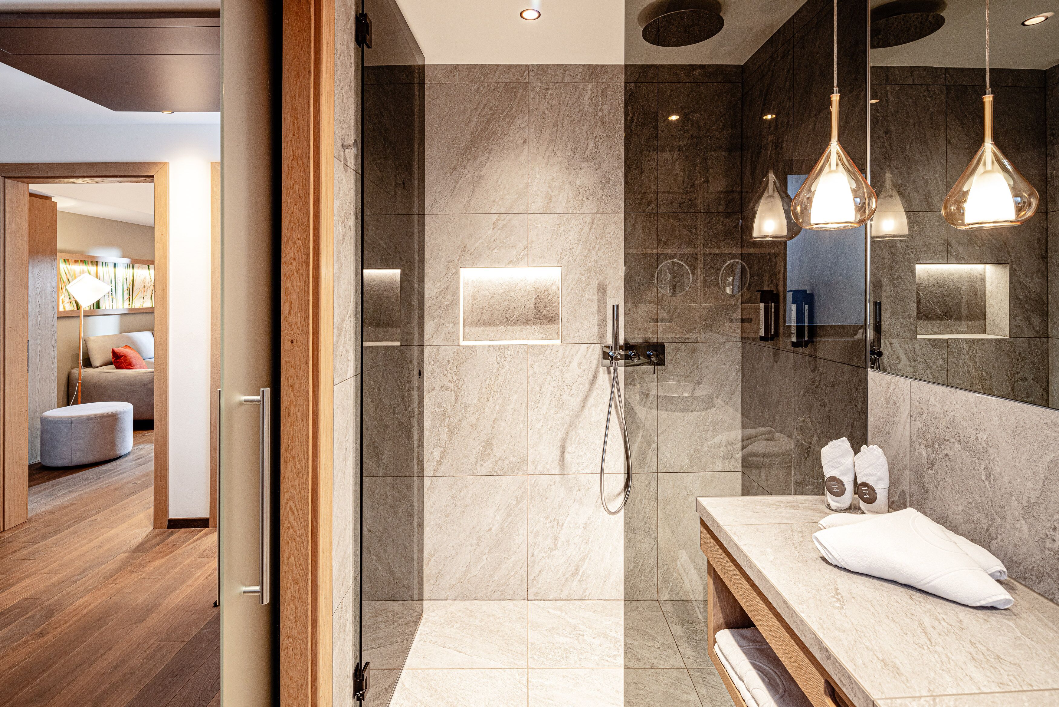 Een moderne badkamer met een ruime douche, een wastafel met spiegel en hanglampen.