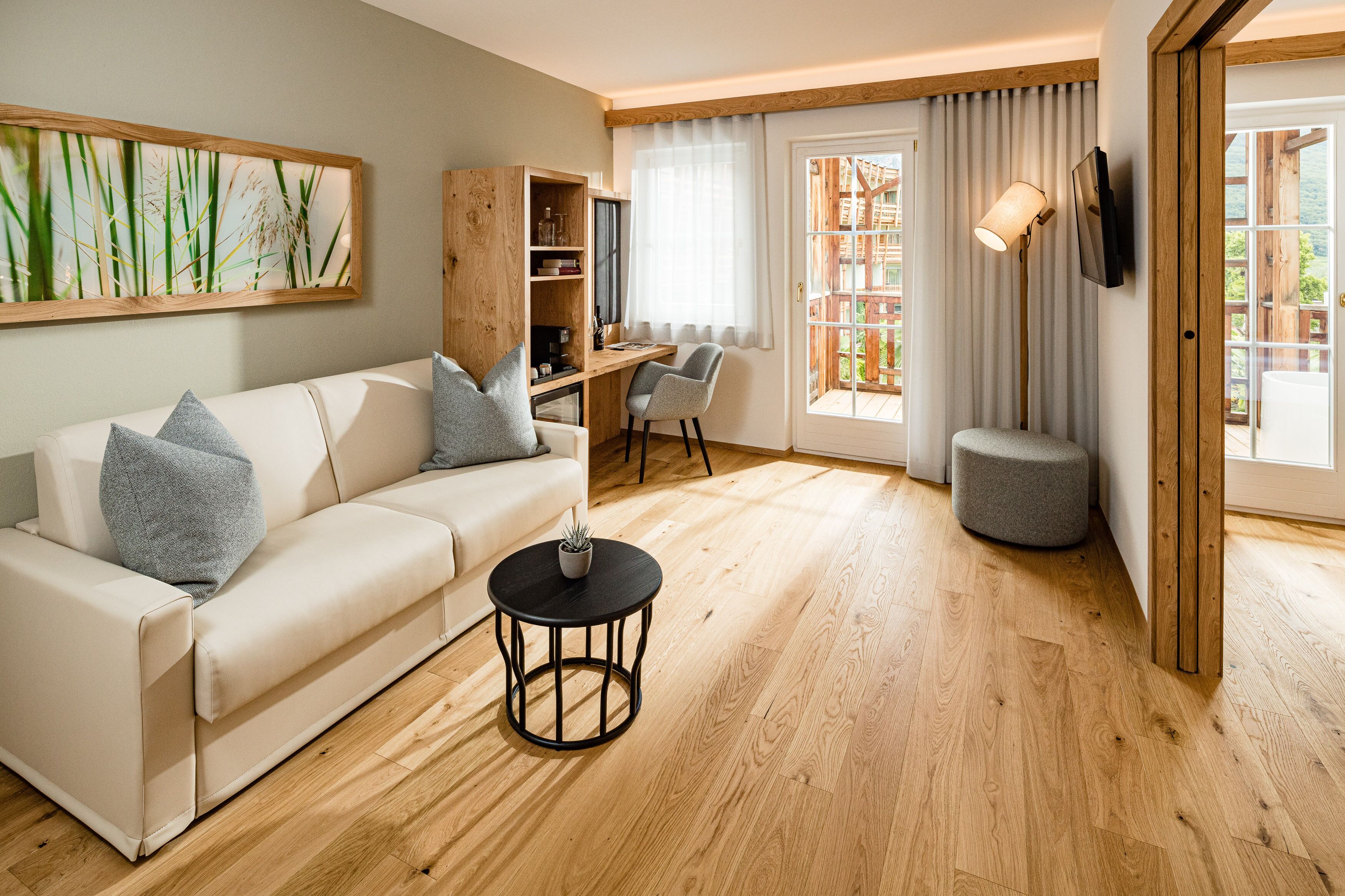 Una sala de estar moderna con un sofá blanco, una mesita redonda y suelo de madera.