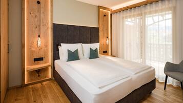 Quarto de hotel moderno com cama grande, painéis de madeira e vista para o exterior.