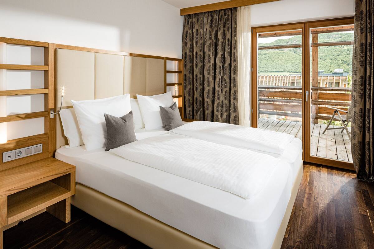 A double bed with a wooden headboard, a bedside table, and a TV on the wall.