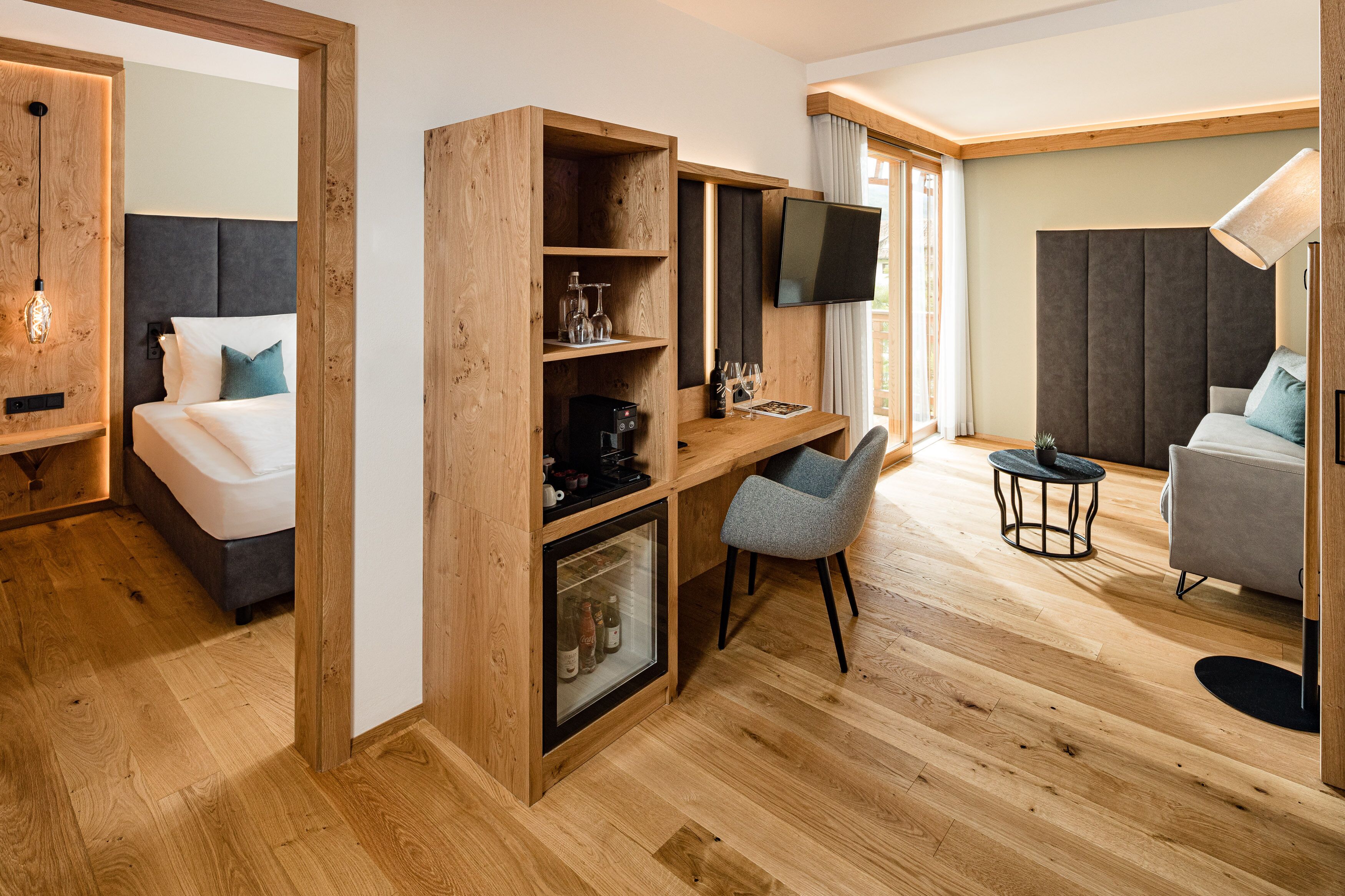 A modern room with a bed, a wooden desk, a television, and a sofa.