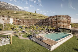 A modern hotel with a pool, outdoor seating, and a view of mountains. - Lake Spa Hotel SEELEITEN (Caldaro Sulla Strada del Vino)