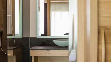 Un baño moderno con un espejo grande, un tocador de madera y una cabina de ducha de vidrio.