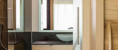 Un baño moderno con un espejo grande, un tocador de madera y una cabina de ducha de vidrio.