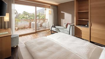 Une chambre d’hôtel moderne dotée d’un grand lit, d’une télévision, d’un bureau et d’un balcon aménagé avec du mobilier d’extérieur.