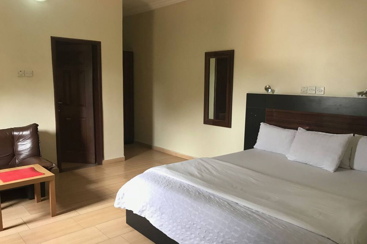 Un dormitorio con una cama, una mesita de noche de madera, una silla y una puerta.