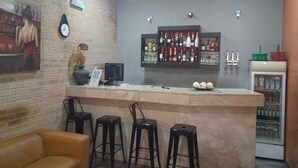 A bar area with a brick wall, a clock, a bar counter, stools, and a refrigerator. - Bayview Resorts and Hotels (Enugu)