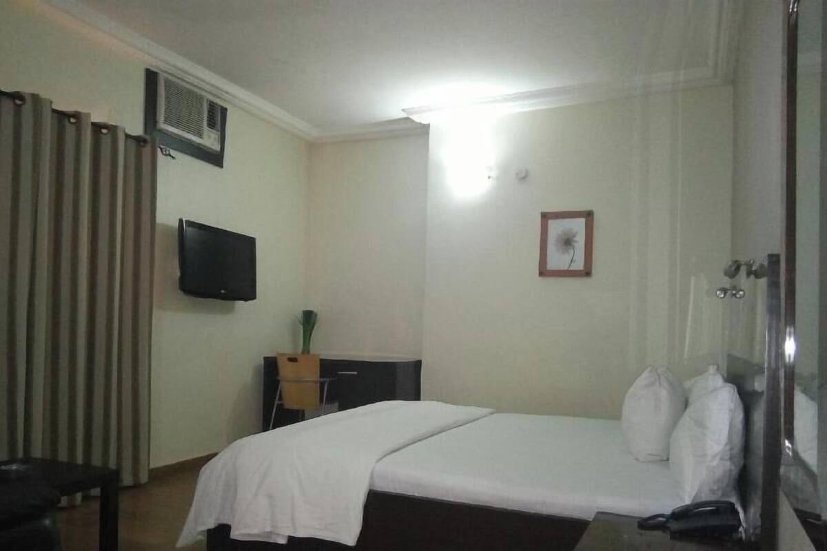 Una habitación de hotel con cama, televisión, escritorio y zona de ducha.
