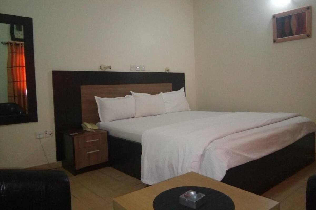 Una habitación de hotel con cama, mesita de noche y una pequeña mesa con bandeja.