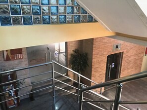 A multi-level interior with a staircase, a brick wall, and a door with an emergency exit sign. - Bayview Resorts and Hotels (Enugu)